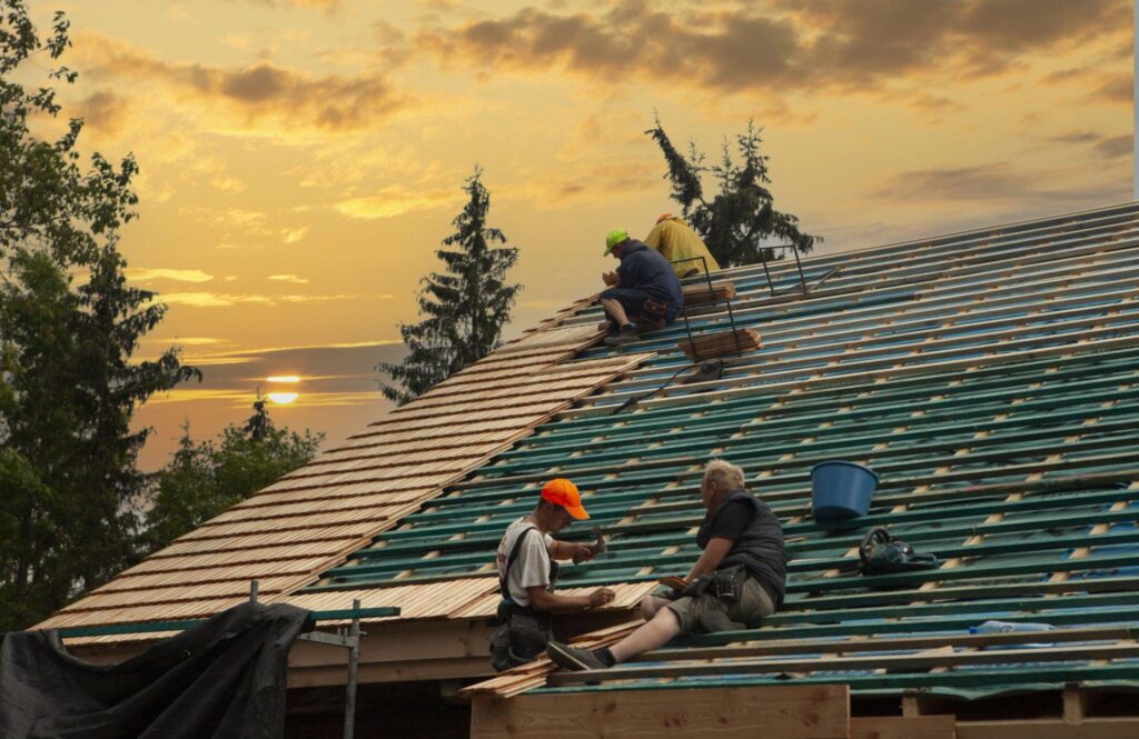 A man with a hardhat using tools repairing a roof